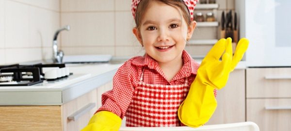 Little Girl holding sponge and smiling in the kitchen